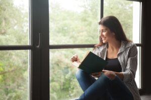 A woman sitting by a window reading a book