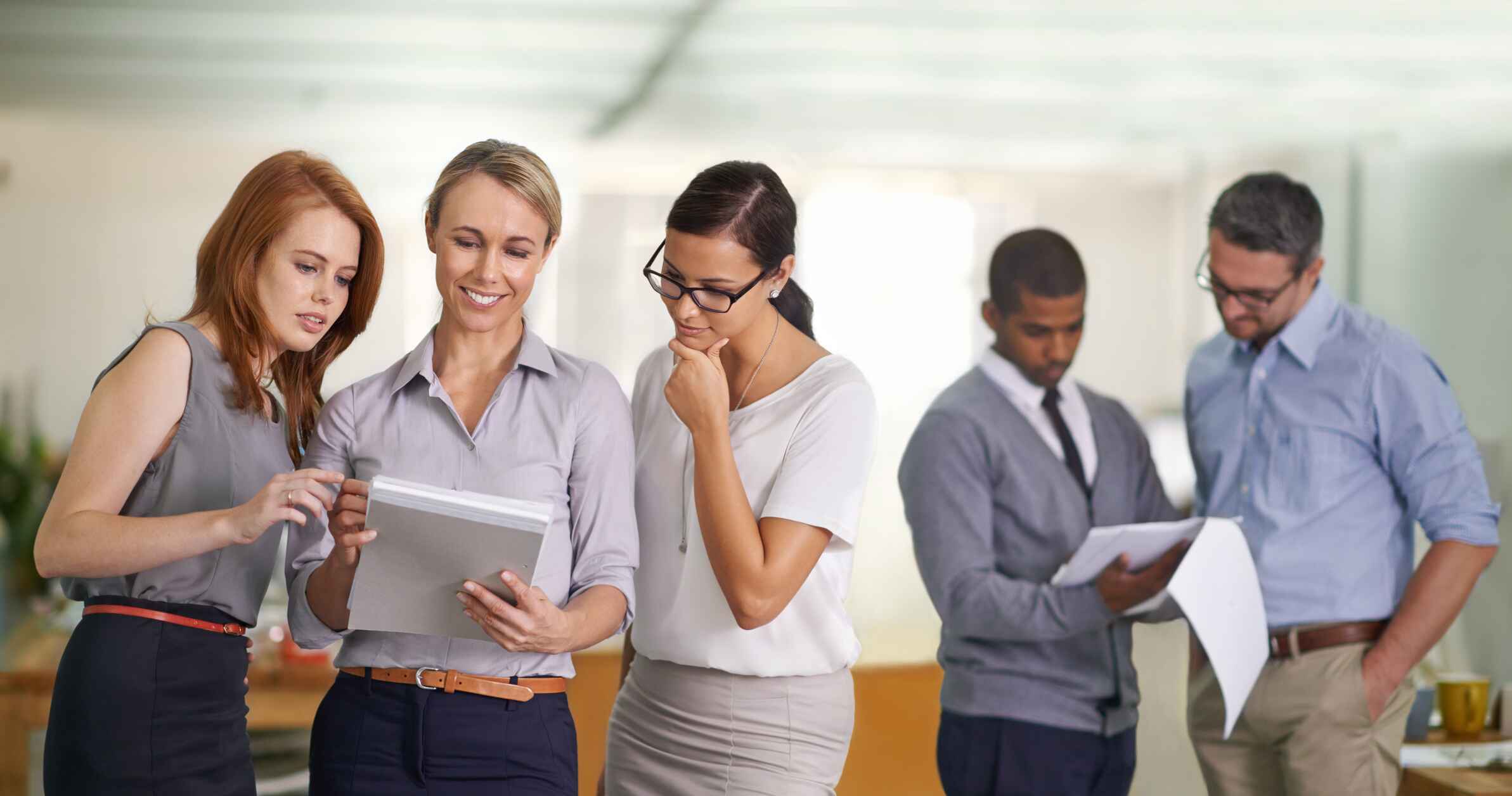 A team of business people surrounding a tablet, actively sharing insights and strategies during a meeting.