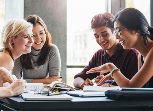 A group of diverse people gathered talking at a meeting table